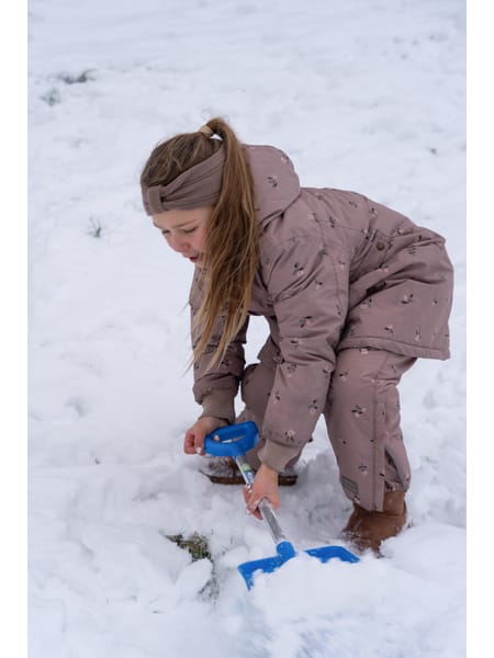 Blå sneskovl med langt håndtag står i snedækket terræn