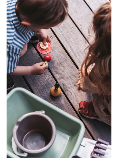 Legetøjsgrøntsager og -frugter i forskellige farver og former på hvid baggrund.