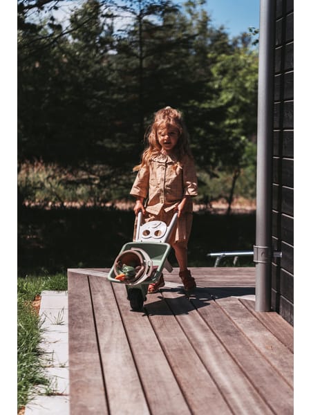 Personer omkring en grøn plastikspand med sandlegetøj på en træterrasse.