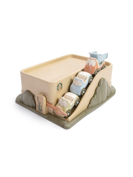 Tre parkerede legetøjsbiler i pastelfarver på en beige/grå parkeringsrampe med sider