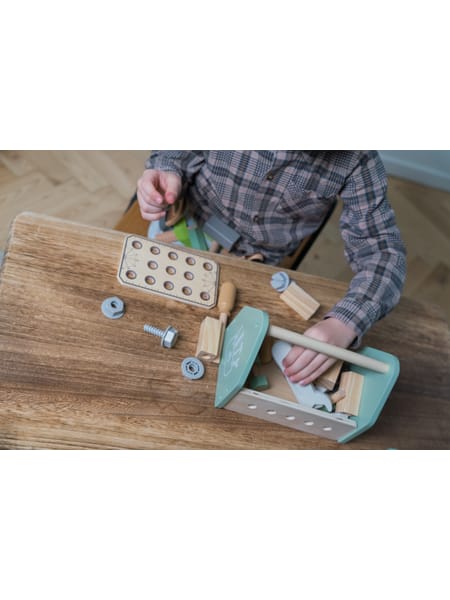 Person bruger turkis værktøjskasse med træklodser på brun bordplade