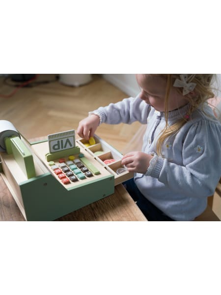 Gammeldags kasseapparat med skuffer og møntbakke på træbord. Hånd rækker ud mod den turkisgrønne kasse.