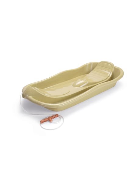 Barn på grøn slæde i snedækket landskab