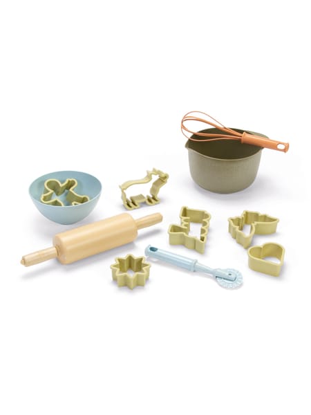 Glad barn ved køkkenbord med skål og kop under madlavning eller bagning