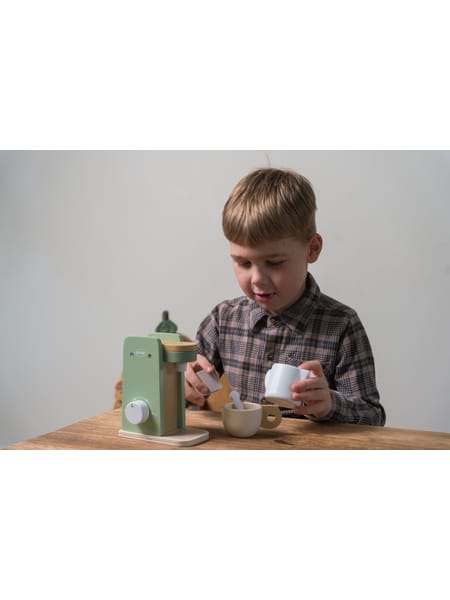 Mintgrøn kaffemaskine med krus og tilbehør på træbord