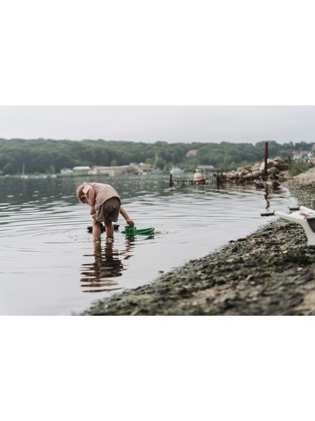Grå havelegetøjssæt med vandkande, spand og båd placeret på træbord