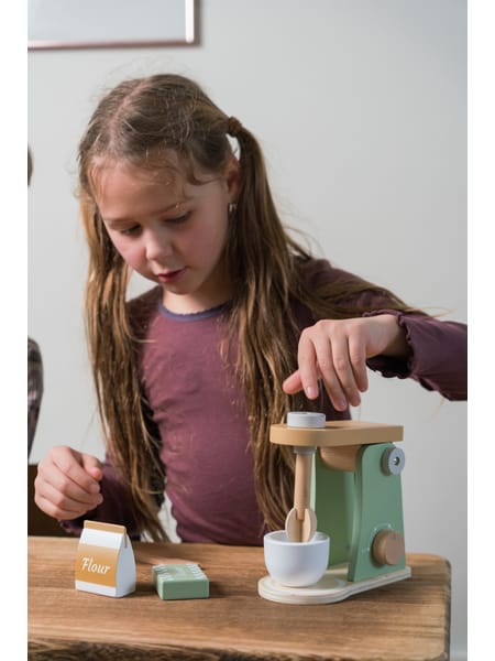 Grøn legetøjsblender med kaffekande og tilbehør på træbord ved siden af krydderier