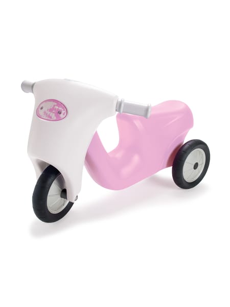 Barn læner sig over lyserød og hvid løbecykel på asfalt