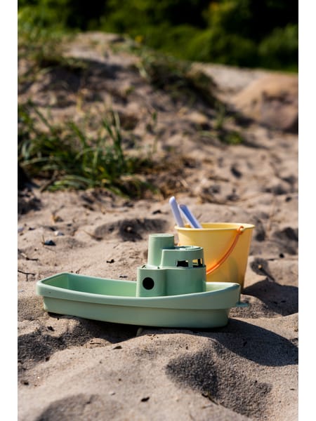Mintgrøn legebåd, gul spand og grå haveredskaber i pastelfarvede nuancer.