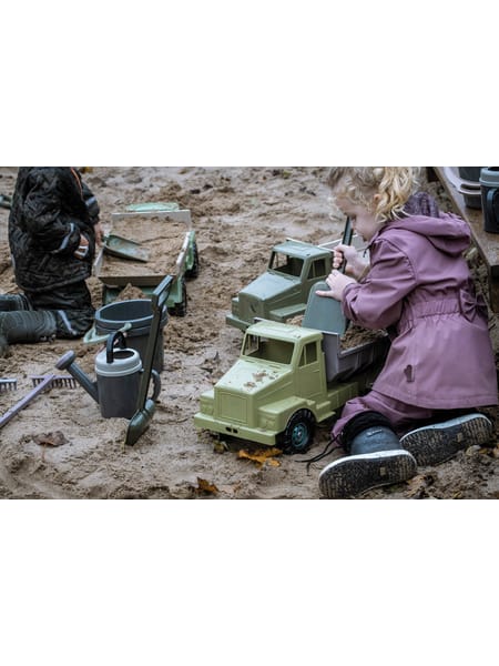 Grøn lastbil med sandlegetøj, skovle og spande i grå og sorte nuancer