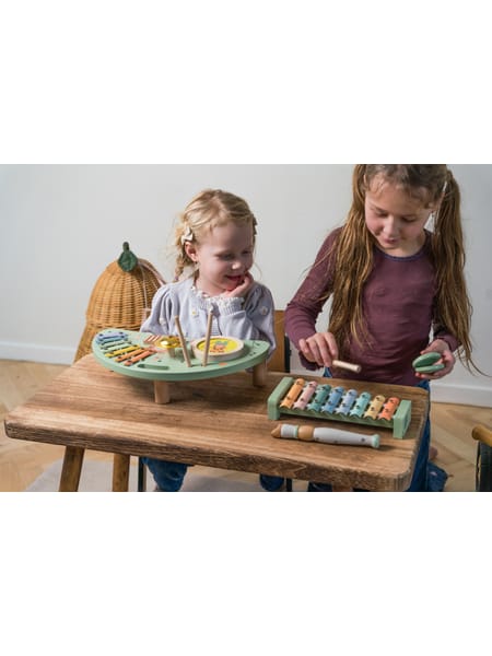 Pastellfarvede musikinstrumenter inklusiv xylofon og fløjte på træbord.