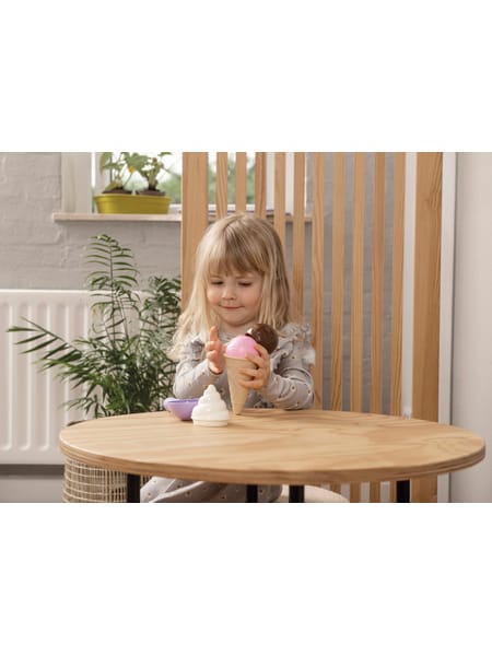 To børn leger med små flasker og legetøj ved en sandkasse udendørs