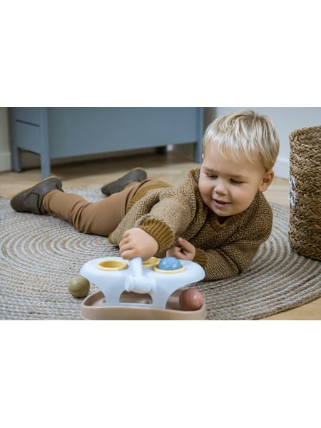 Barn på gulvtæppe leger med farverigt hammerbræt-legetøj med runde knapper