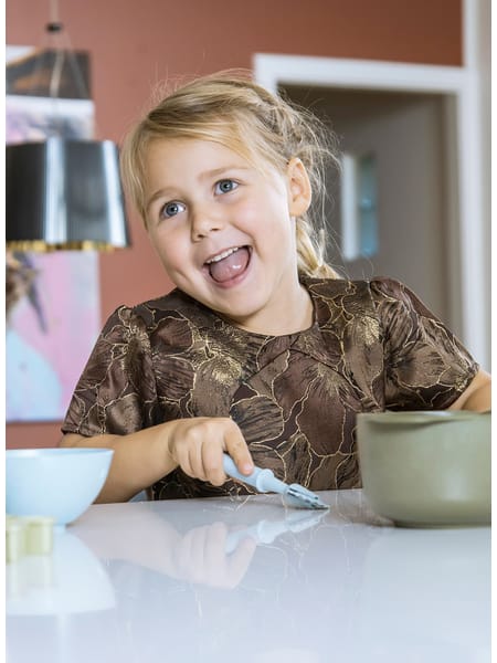 Barn ved bord med småt bageudstyr og dej foran sig