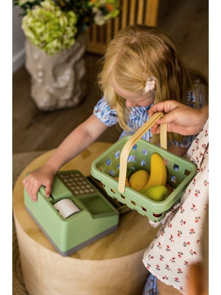 Grøn indkøbskurv med frugt i plastik: bananer, appelsiner, æbler og jordbær