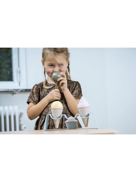 Person laver is med legetøjs-ismaskine og holder plastik-isterninger over små blå og grå beholdere.