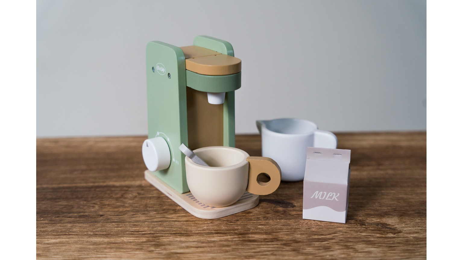 Mintgrøn kaffemaskine med krus og tilbehør på træbord