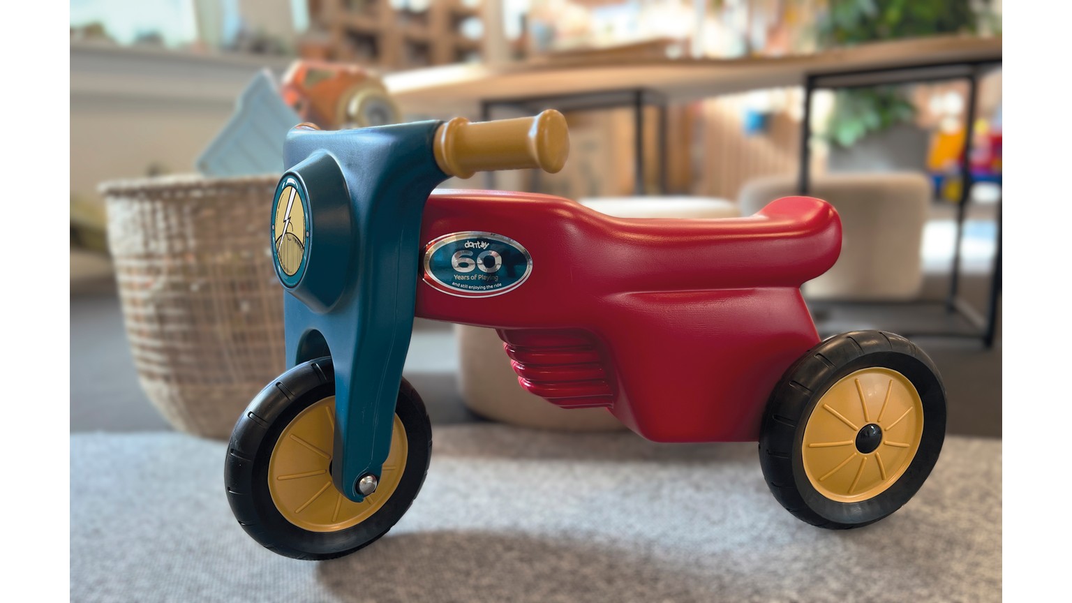 Rød og blå trehjulet motorcykel-legetøj på gulgrå baggrund