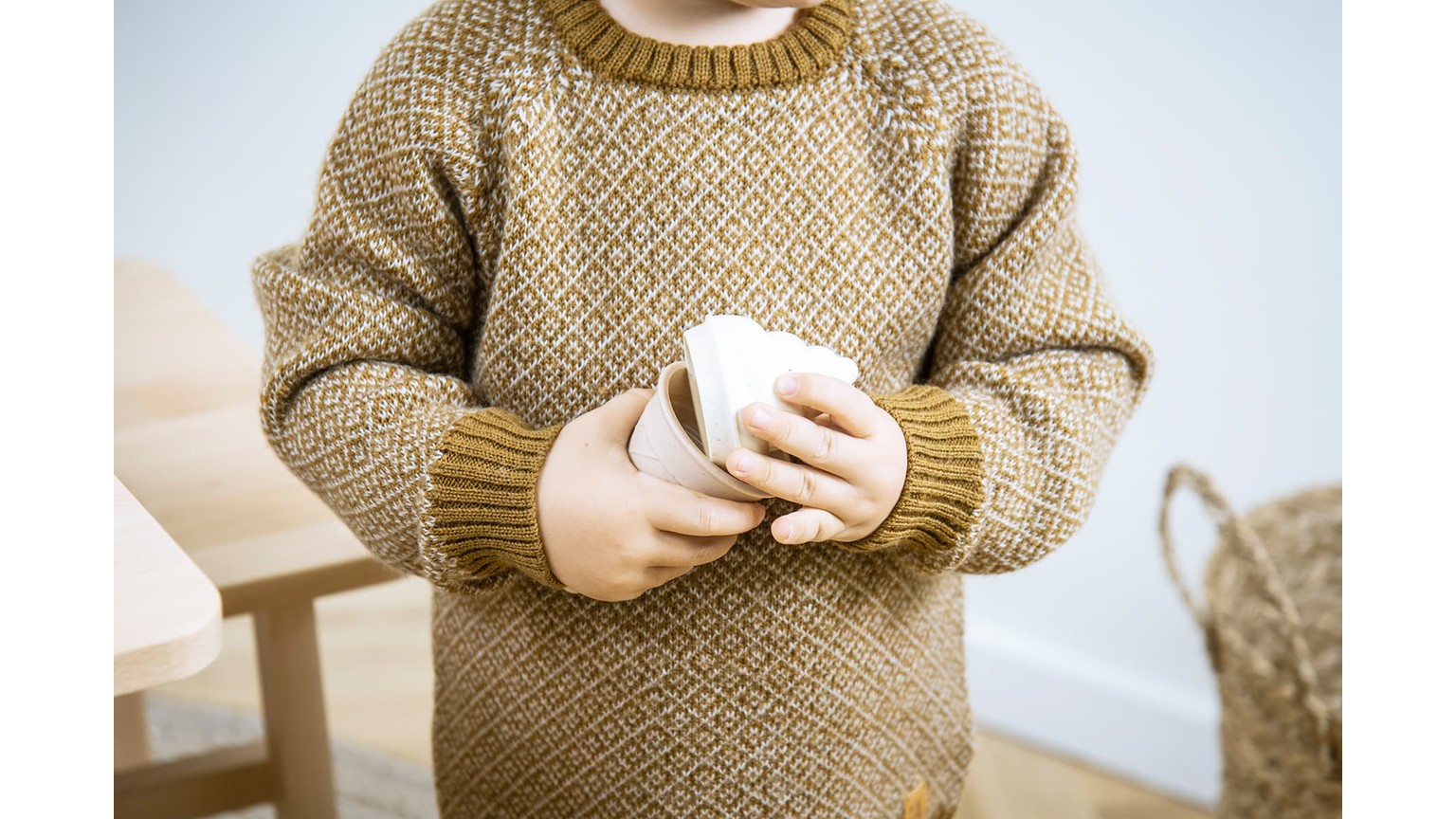 Person iført brun strikket sweater holder noget i hænderne