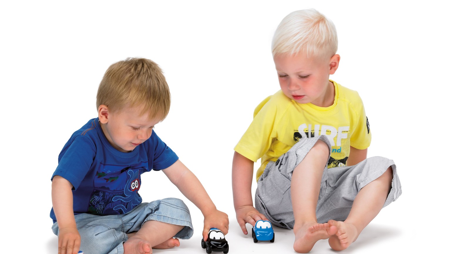 To børn sidder på gulvet og leger med små farverige biler