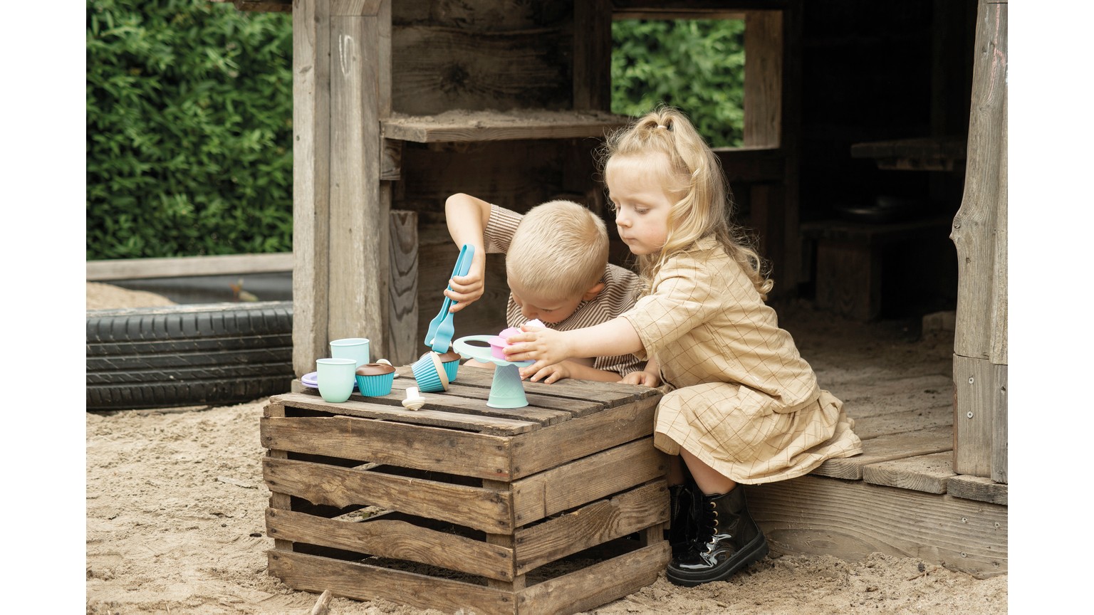 Barn leger med miniature teservice på rustik trækasse udendørs