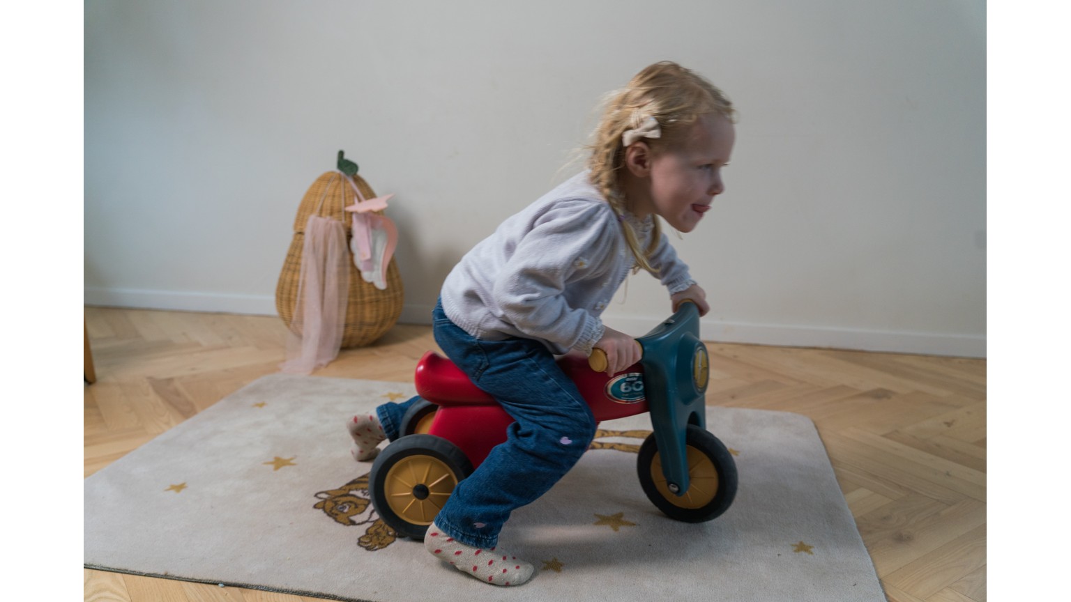 Lille blå og rød motorcykel på træbund i stue med køreklar rytter