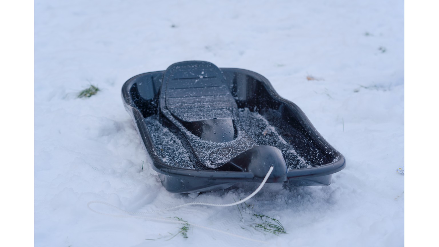 Sort slædebakke på snedækket underlag.