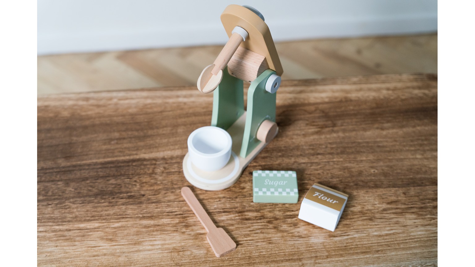 Grøn køkkenblender med tilbehør og hvid kop på træbord