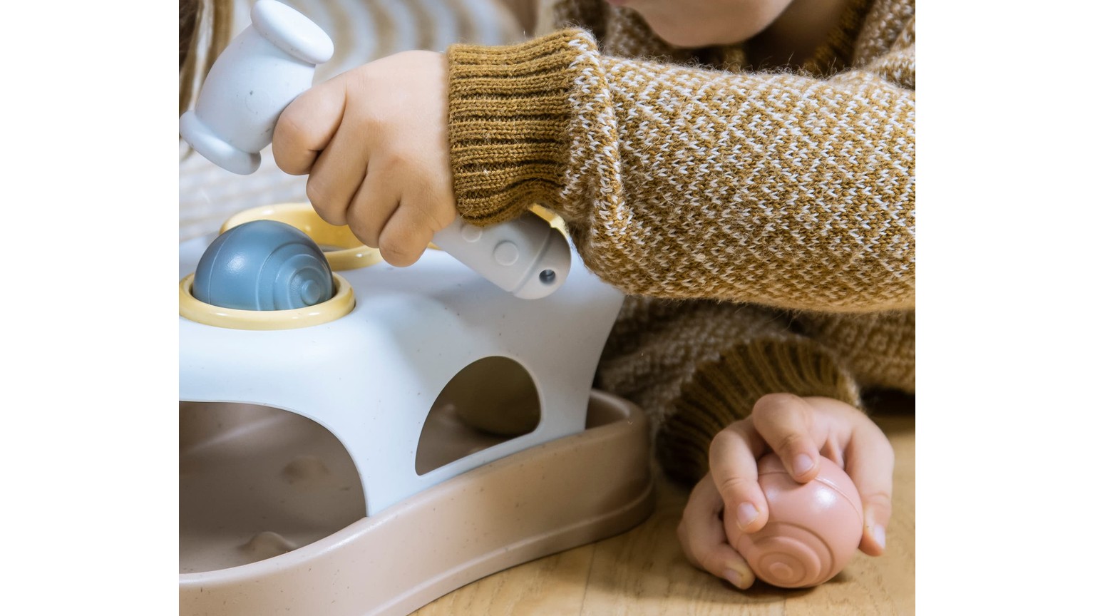 Person med strikkeærme leger med hvidt hammerbræt med blå kugler