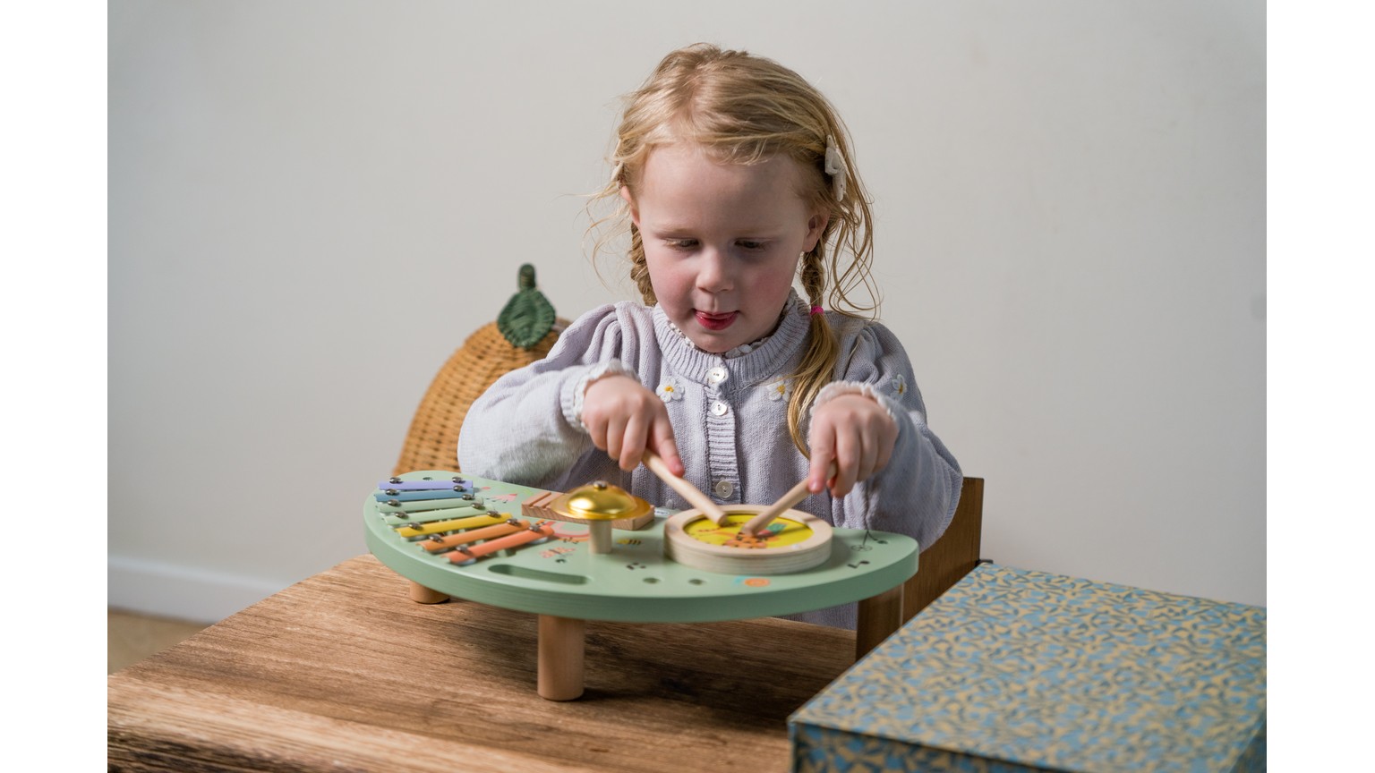 Barn ved træbord med grøn og orange madlegetøj på rund plastiktallerken.