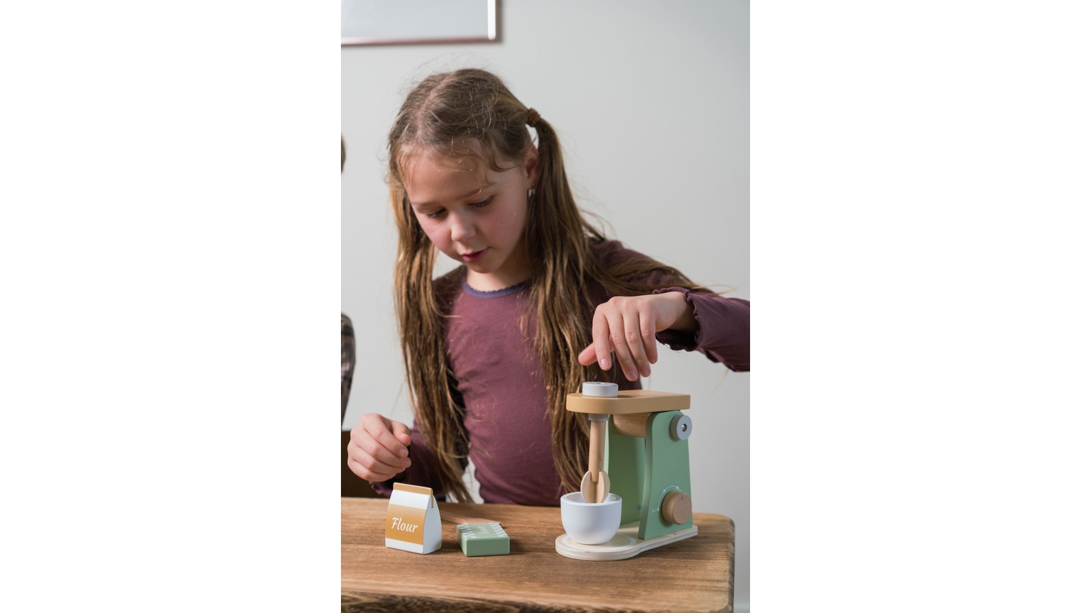 Barn leger med hvid køkkenmaskiner i miniformat på et bord