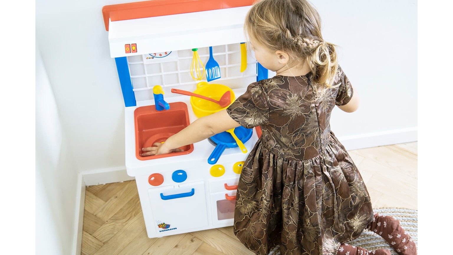 Børnekøkken i hvidt med gul kande og blå detaljer, hvor et barn leger ved legekomfuret.