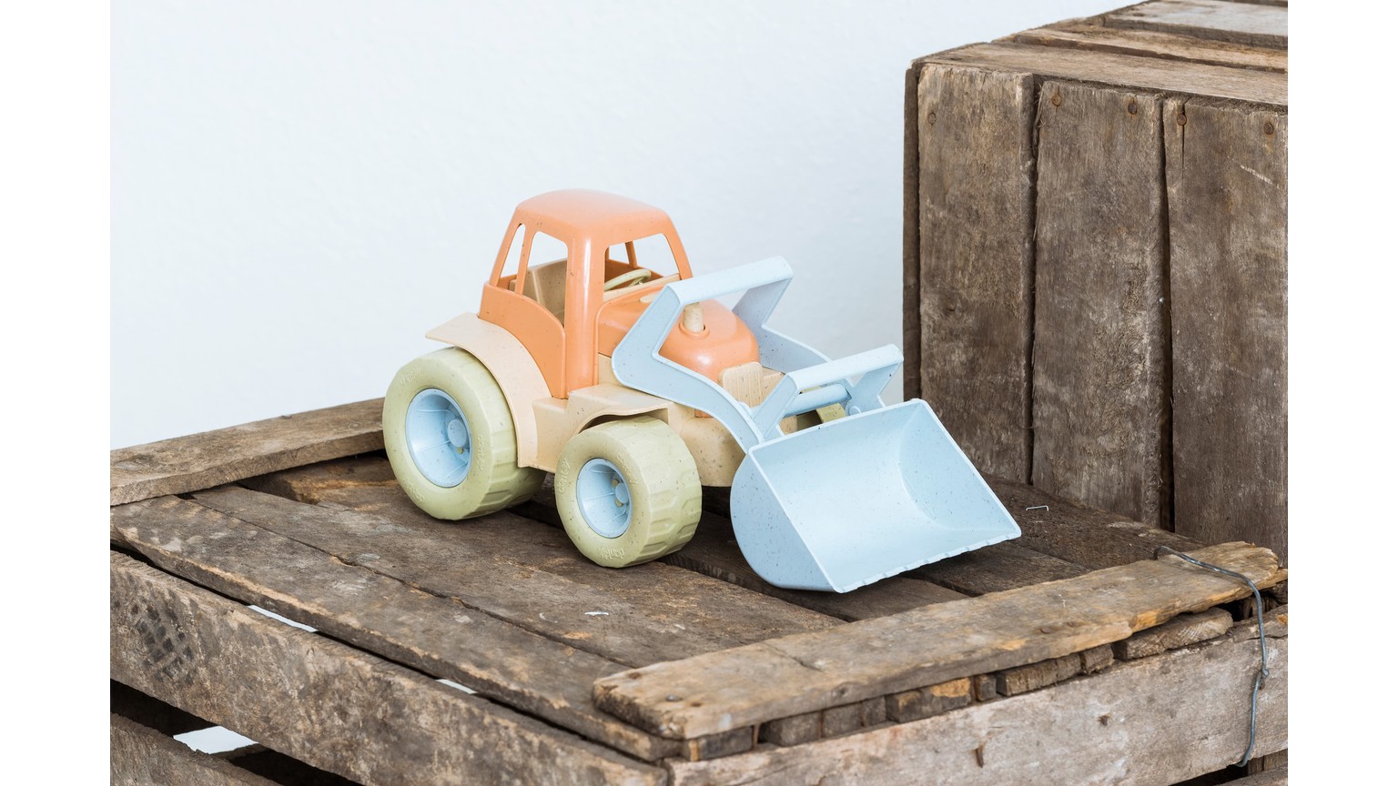 Lyseblå og orange legetøjstraktor med skovl, placeret på træoverflade