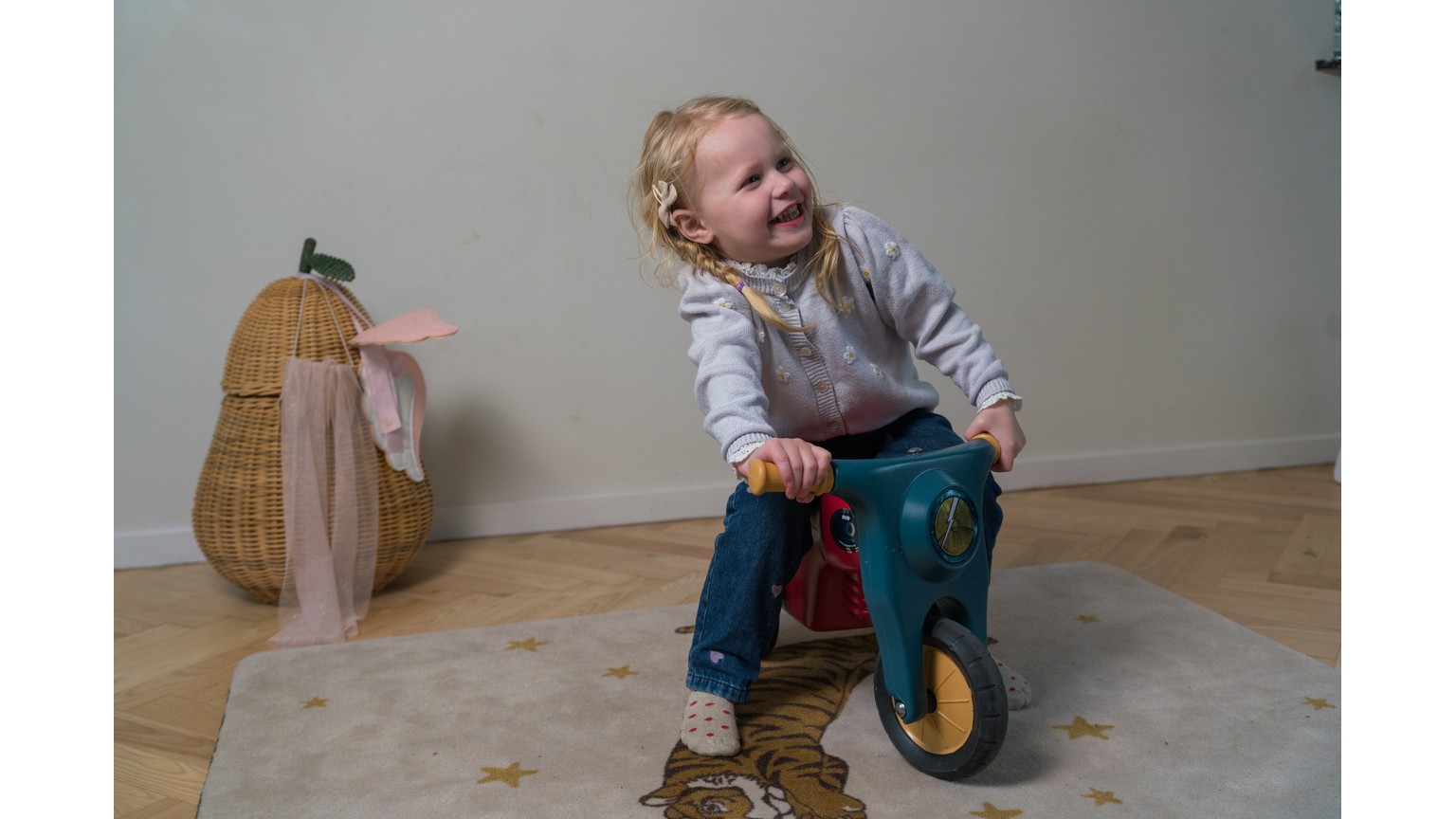 Barn på rød trehjulet motorcykel i minimalistisk indrettet rum med trægulv