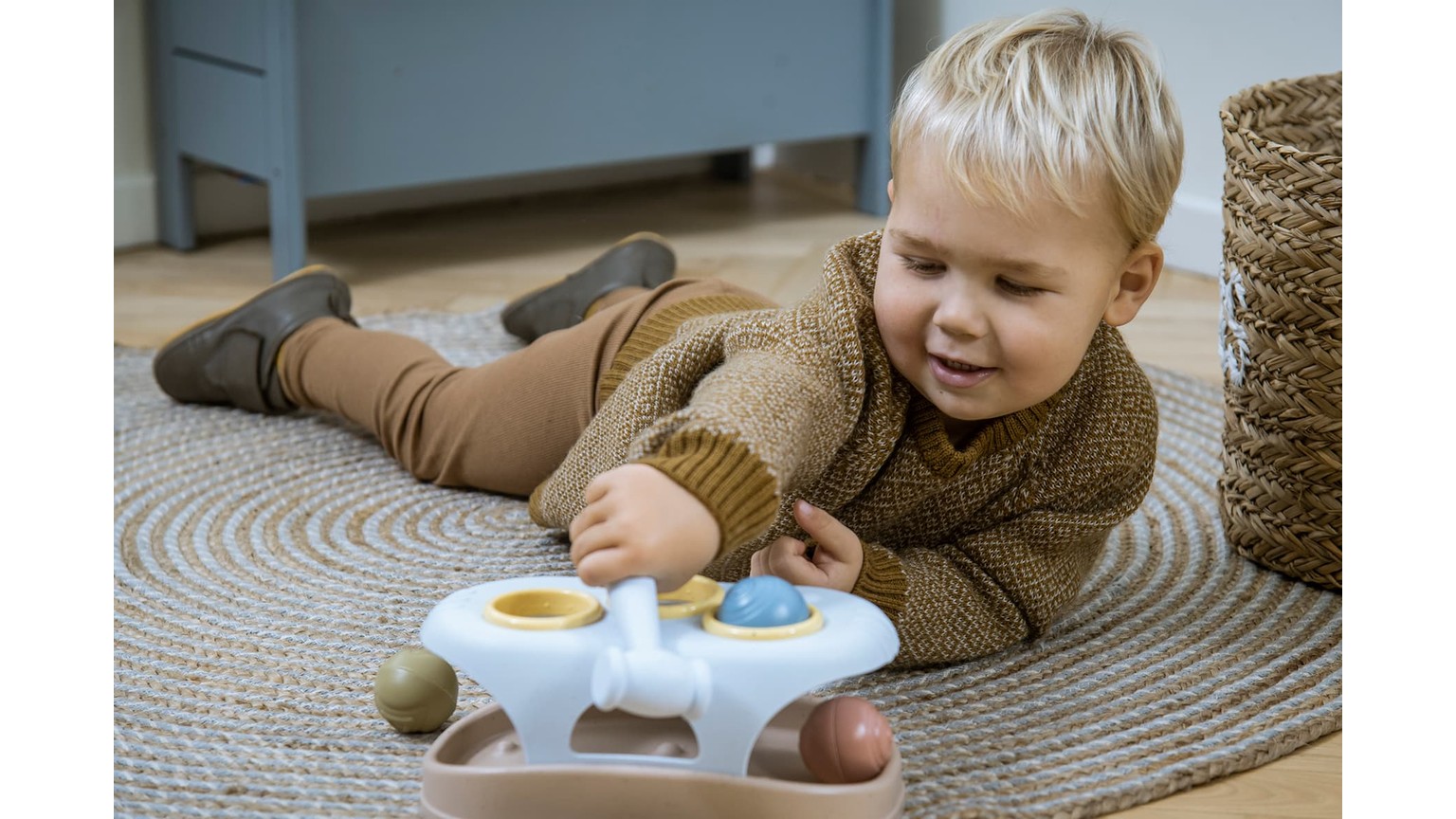 Barn på gulvtæppe leger med farverigt hammerbræt-legetøj med runde knapper